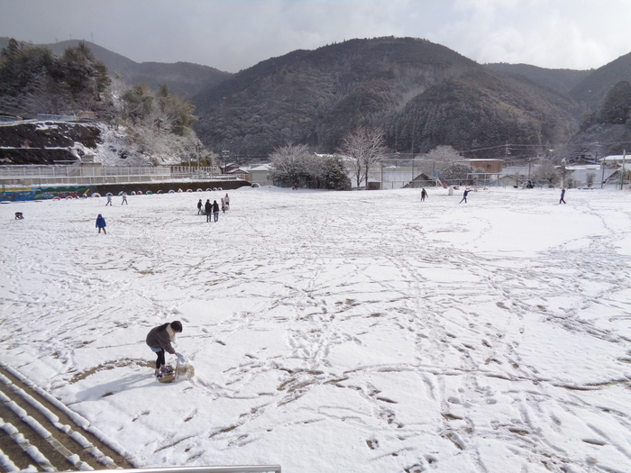 雪の残る校庭で遊ぶ児童たち